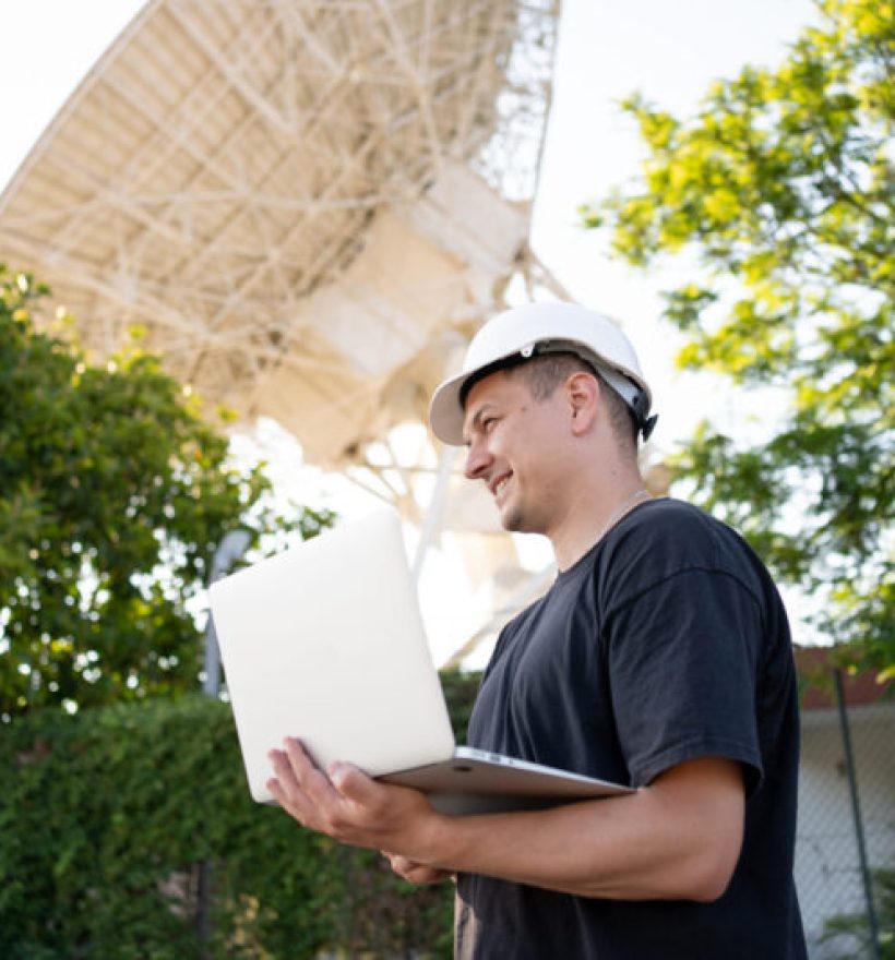 Engineer testing earth based astronomical radio telescope use laptop. Radio telescopes used in science for space observation and distant objects exploring. Big satellite dishes